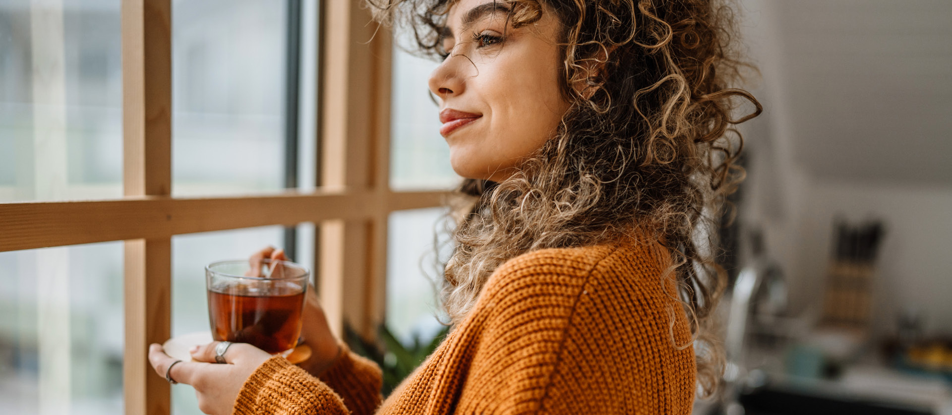vrouw staart uit een raam met een kop thee