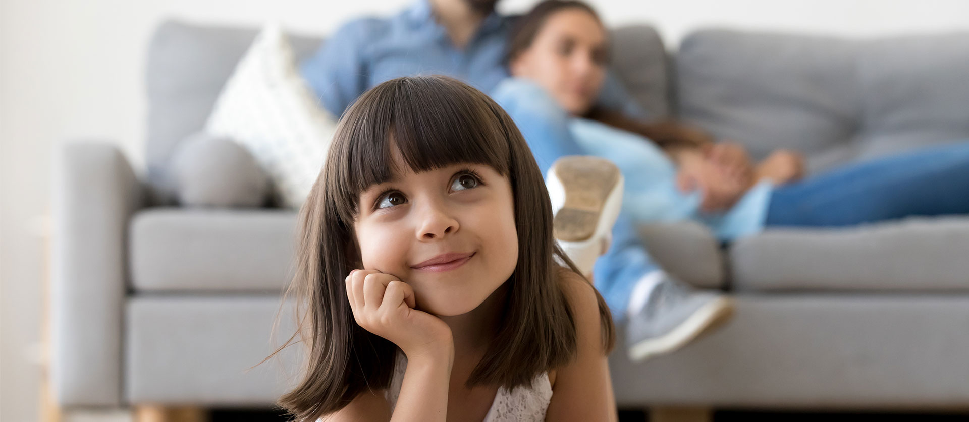 jong meisje ligt in de woonkamer op de grond en kijkt dromerig omhoog