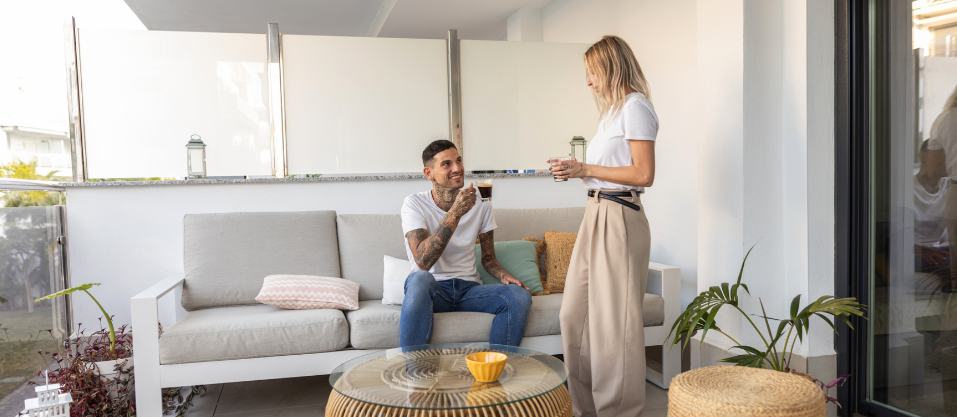jong stel zit op hun balkon een kop koffie te drinken