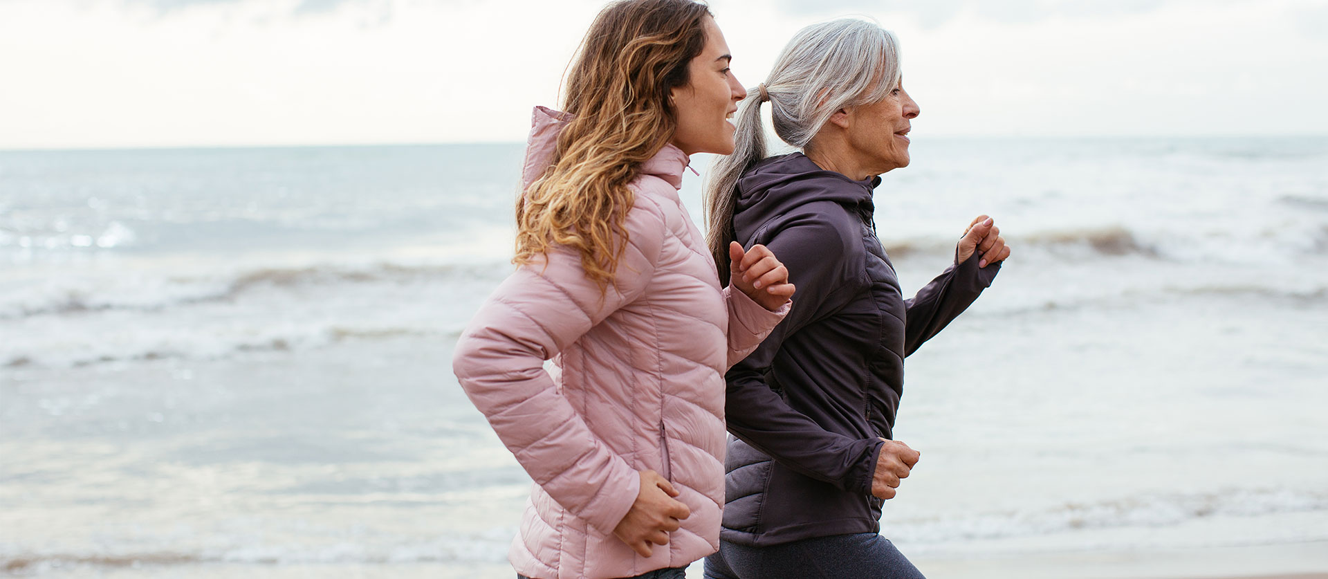 Moeder en dochter joggend op het strand
