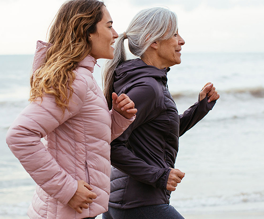 Moeder en dochter joggend op het strand