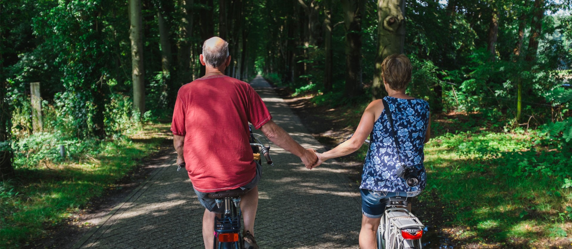 een ouder stel op de fiets die handen vasthouden