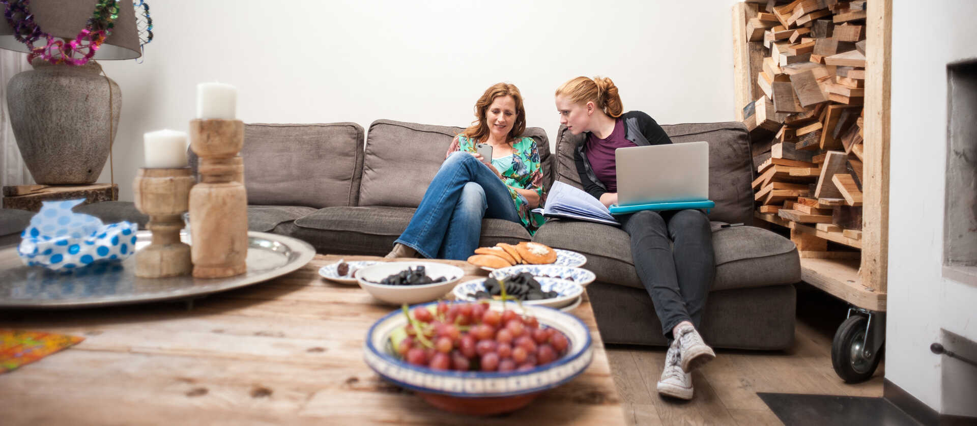 moeder en dochter zitten op de bank en de dochter heeft een laptop op schoot