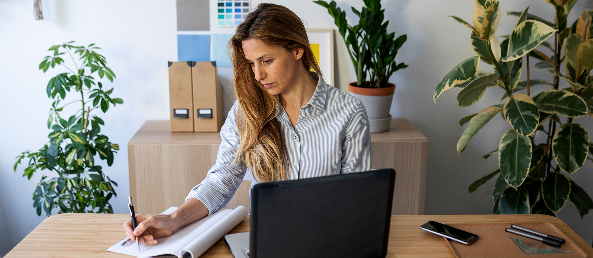 Een vrouw zit aan de keukentafel achter haar laptop