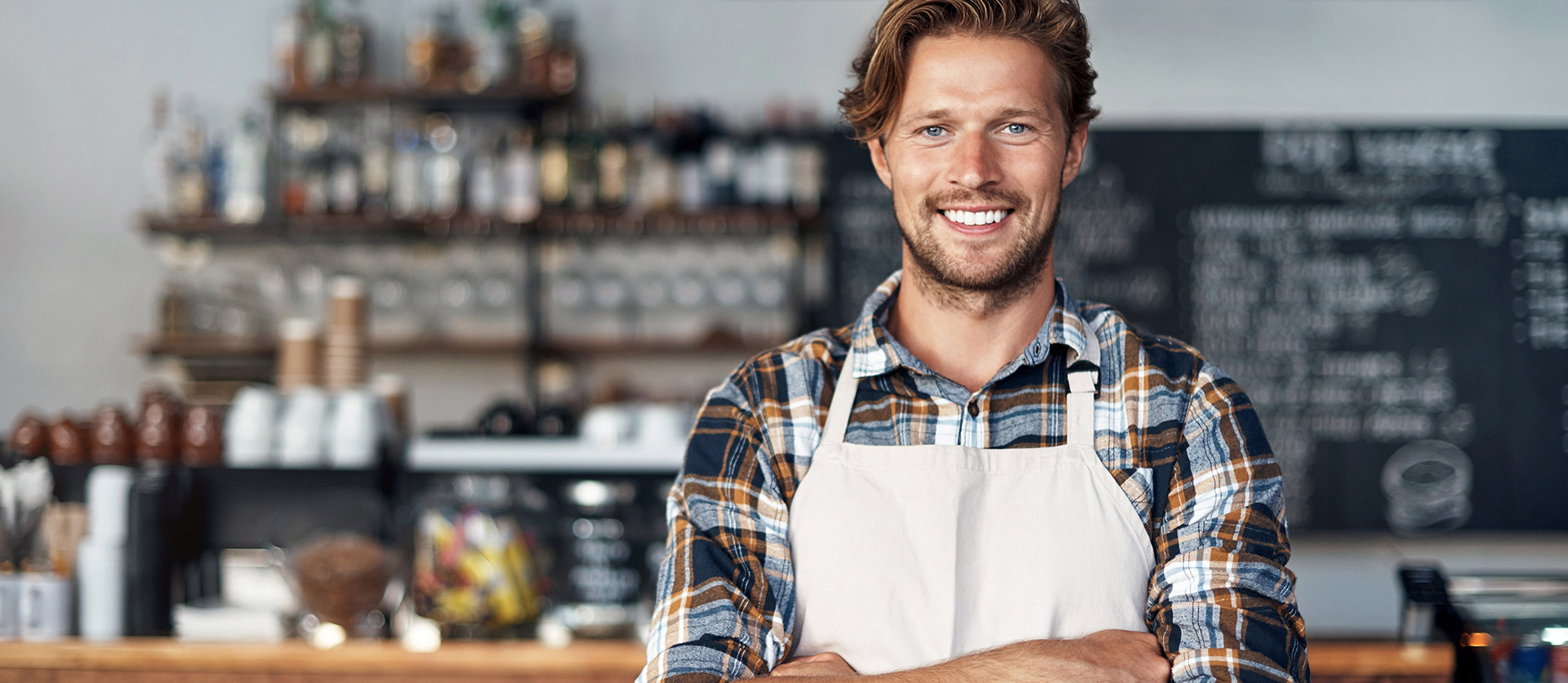 Mannelijke barista staat voor de bar met zijn armen over elkaar