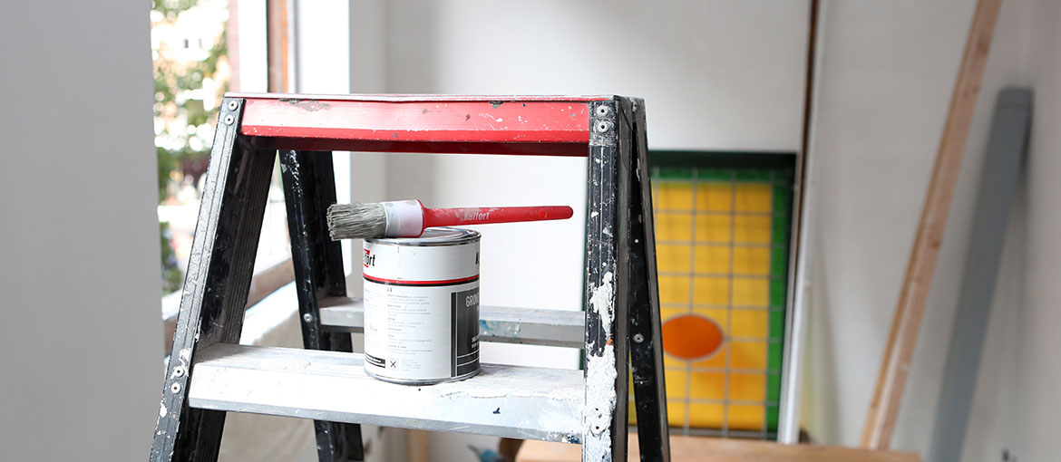 verf kwast ligt op een verfblik op een ladder