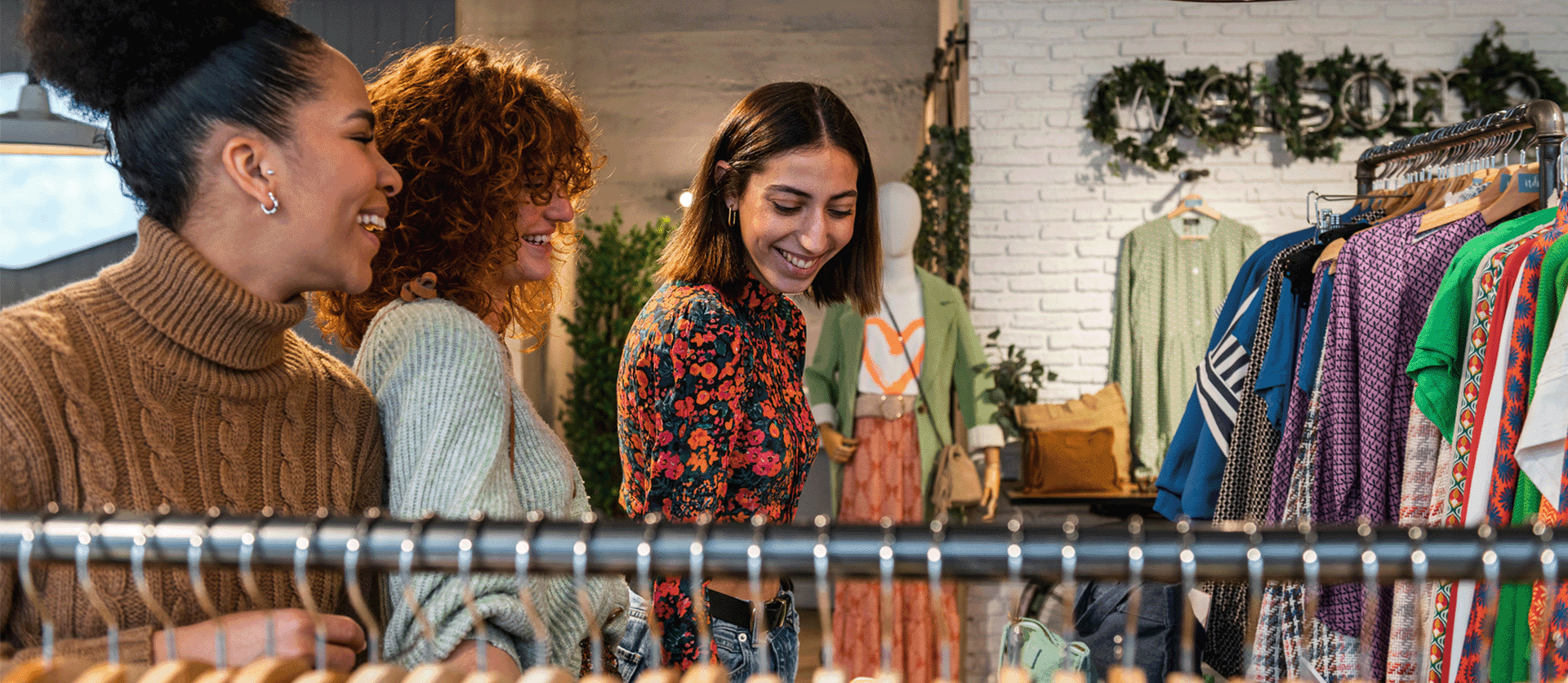 drie vrouwen zijn aan het shoppen en kijken naar kleding op een kledingrek